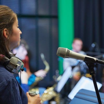 singer wearing headphones standing by microphone